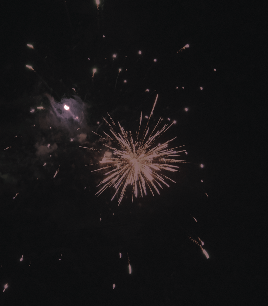 City fireworks and eclipse combined — tension between celebration and cosmic stillness.
